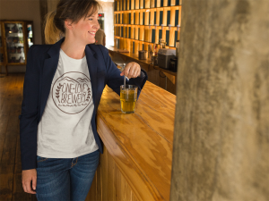 Smiling Middle Age Woman Wearing A Round Neck T Shirt Mockup While At A Bar A15772 - Stickersandmore.com